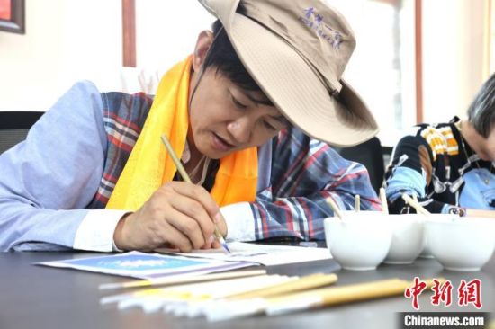 图为香港媒体代表体验唐卡绘制。张海雯摄