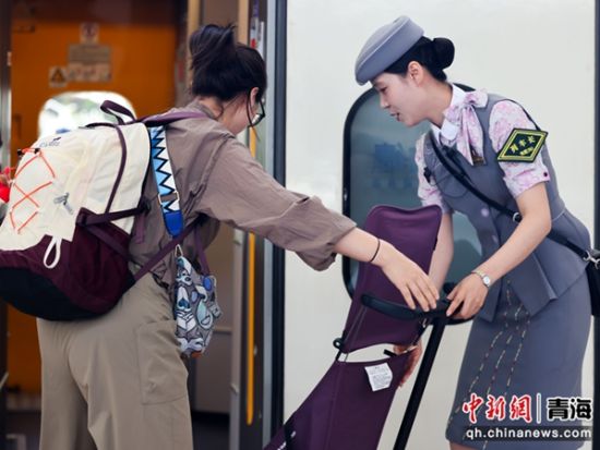 图为刘凯月在列车门口帮助旅客提拿行李。 李磊摄 图为刘凯月在列车门口帮助旅客提拿行李。 李磊摄