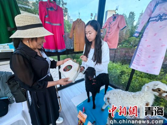 图为工作人员为游客介绍民族特色包包。李隽 摄