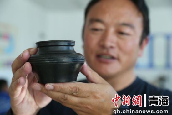 图为果洛谢格太展示黑陶作品。张忠苹摄