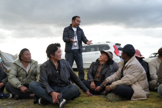 图为巴登求扎向牧民介绍牦牛险业务。 何欣然摄