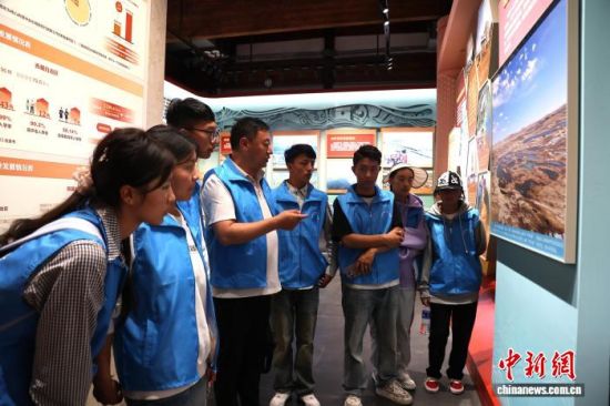 图为展厅中加强生态环境保护的展示区域，青梅多杰向学生讲述青海在保护三江源方面所做出的努力与成就。张海雯 摄